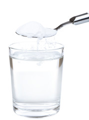 Spoon of baking soda over glass of water, isolated on white