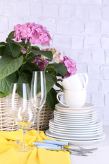Blooming hydrangea and utensils on table on grey wall