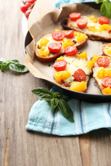 Tasty bruschetta with tomatoes on pan, on old wooden table