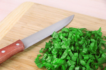 Chopped greens with knife on cutting board