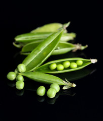 Fresh green peas isolated on black background