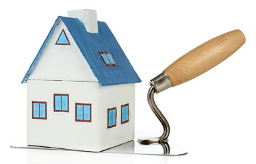 Wooden toy house on trowel and tiles, isolated on white
