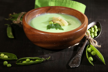 Tasty peas soup on wooden table with dark light