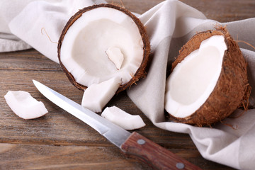 Broken coconut with knife and napkin on wooden background