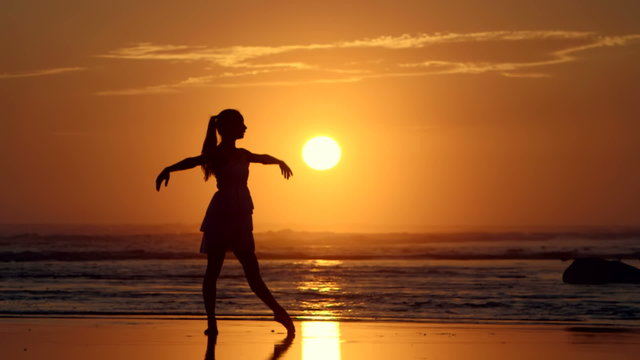 Silhouette of woman dancing Ballet on Beach at Sunset