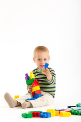 Little cute boy playing with building blocks. Isolated on white.