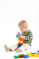 Little cute boy playing with building blocks. Isolated on white.