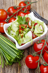 Bowl of fresh salad on rustic wooden table