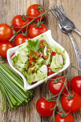 Bowl of fresh salad on rustic wooden table