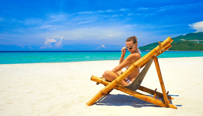 Happy attractive young  woman in bamboo chair at the beach