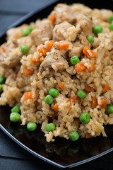 Pilaf with chicken, carrot and green peas on a glass plate