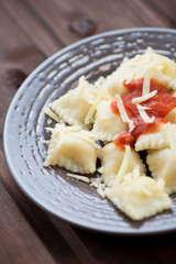 Cheese ravioli with tomato sauce on a glass plate, vertical shot