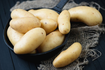 Cast-iron frying pan with raw potato, horizontal shot, close-up
