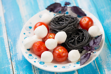 Mozzarella balls, black tagliatelle, cherry tomatoes and basil