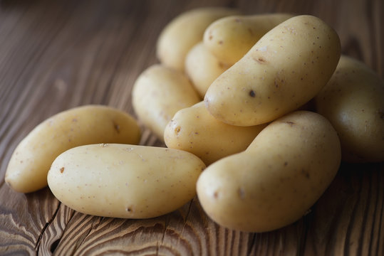 Raw potato over wooden background, close-up, horizontal shot