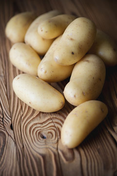 Vertical shot of freshly harvested potato over wooden surface