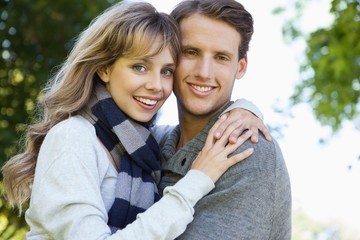 Cute couple embracing and smiling at camera in the park