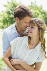 Attractive couple embracing and smiling in park