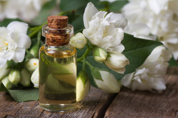 Fototapeta na wymiar bottle of fragrant jasmine essence closeup and flowers