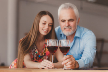 young girl and senior man holding wine glasess