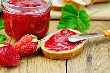 Bread with strawberry jam and a knife on board