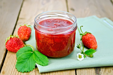 Jam of strawberry with berries and leaf on board