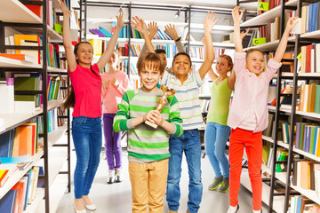 Happy boy holds cup and other children jump