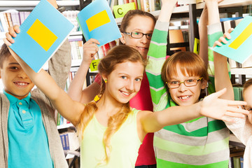 Laughing pupils with exercise books up in library