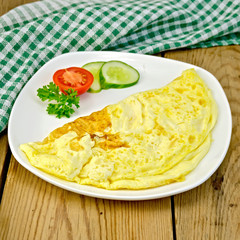 Omelet with vegetables and green napkin on board