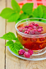 Tea with raspberries in glass cup and napkin on board