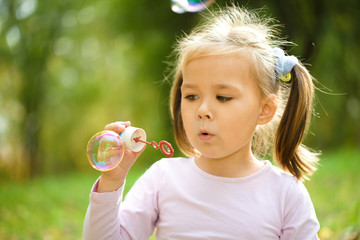 Little girl is blowing a soap bubbles