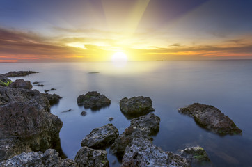 Fototapeta na wymiar Sunset over the silky water with rocks