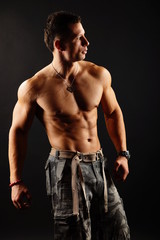 Fototapeta na wymiar Handsome muscular man poses on the dark background