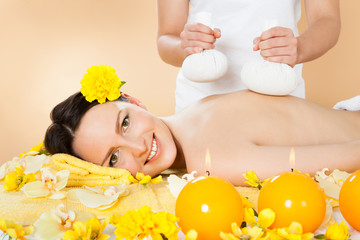 Woman Receiving Massage With Herbal Compress Stamps At Spa