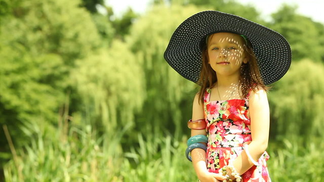 Little girl child kid putting on straw hat outdoor