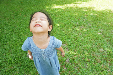 Little girl is feeling the wind on green grass