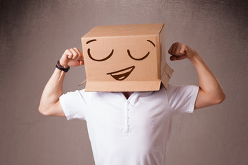 Young man gesturing with a cardboard box on his head with smiley