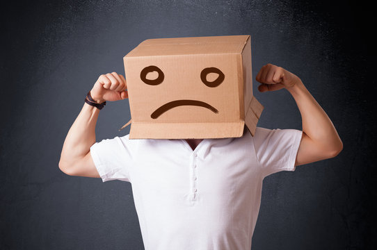 Young man with a brown cardboard box on his head with sad face