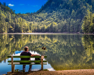 Person sitzend auf Bank, Blick auf den See