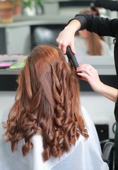 Fototapeta premium styling curls and weaving French braid on long hair in salon