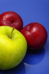 Plum fruit and green apple over blue background