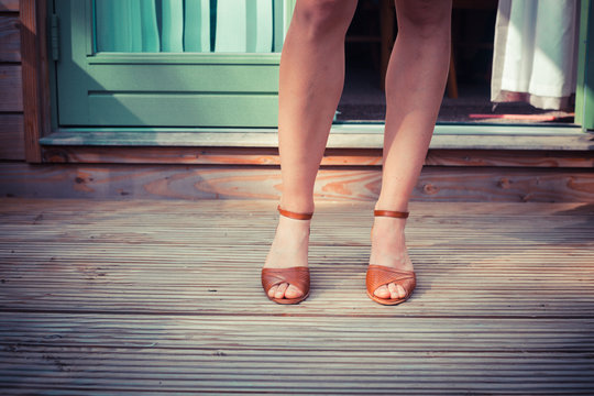 The legs of a woman standing on a porch