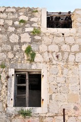Wall of abandoned, damaged, old house with two windows