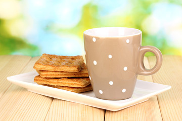 Cup of tea and cookies on wooden table on bright background