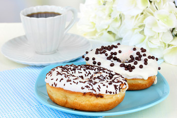 Sweet donuts with cup of tea on table close-up