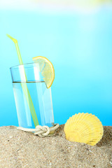 Beach cocktail in sand on blue background