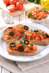 Delicious bruschetta with tomatoes on plate on table close-up