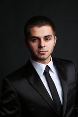 Handsome young man in suit on dark background