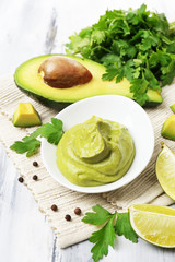 Fresh guacamole in bowl on wooden table