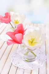 Beautiful tulips in bucket in vase on table on light background
